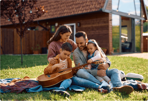 Happy family sitting outside in the grass on a blanket on a bright spring day